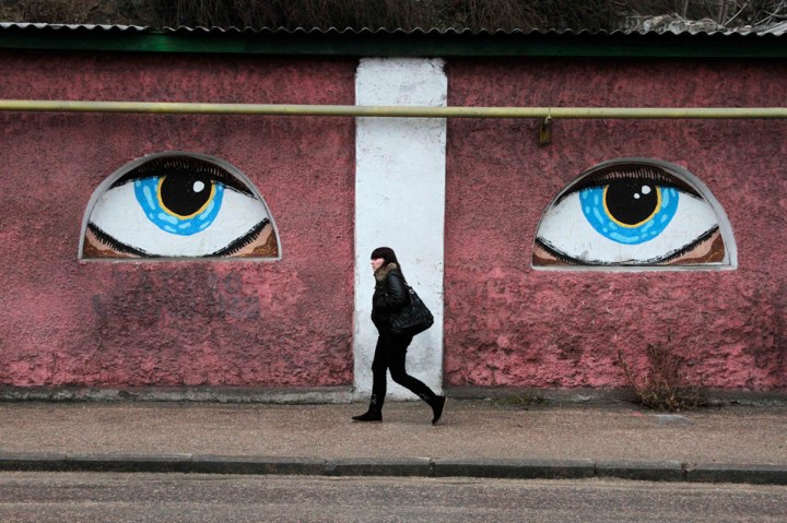 A woman walks past a building decorated with eyes in Crimean city of Sevastopol